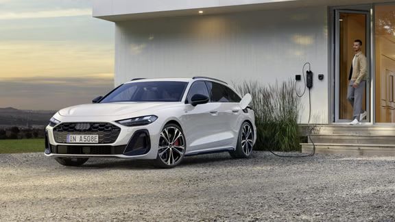 Der A5 Avant e-hybrid ist an eine Ladestation an einem Wohnhaus angeschlossen.