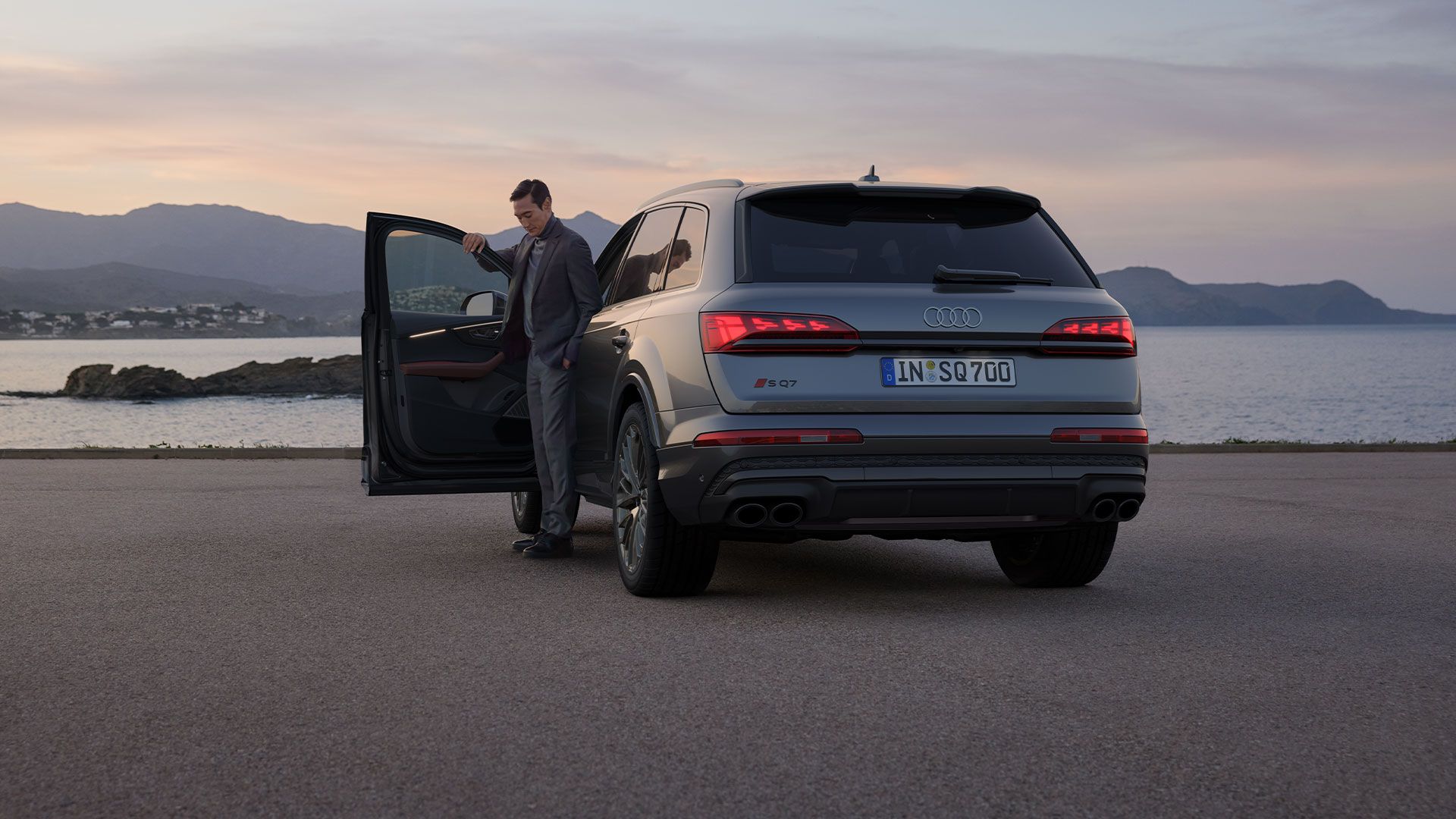 Seitliche Heckansicht eines silbernen Audi SQ7 SUV mit einem Mann