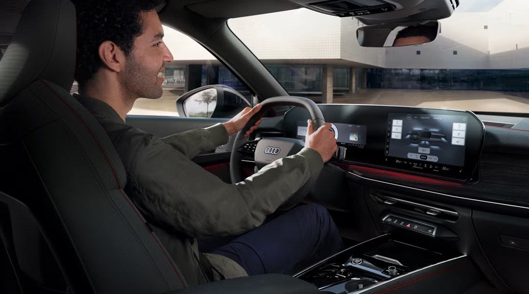 Blick von schräg hinten auf das Cockpit des Q3 Sportback, ein junger Mann sitzt am Lenkrad.
