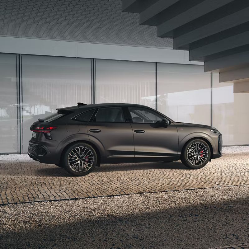 Der Audi Q3 Sportback steht unter einer Treppe. Das Auto ist von der Seite zu erkennen und es zeigt die genauen Details der Außenseite.